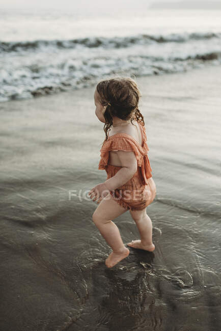 Young toddler girl with pigtails walking into the ocean — Stock Photo