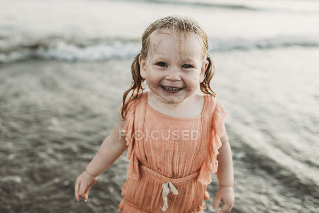 Портрет дівчинки-малятка, яка посміхається в океані на заході сонця — стокове фото