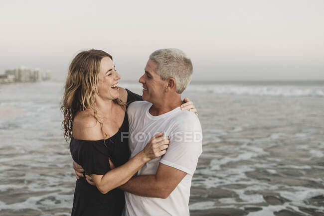 Pareja casada mirándose en la playa del océano - foto de stock