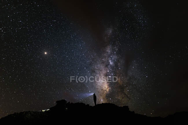 Silueta de un montañero mirando a la Vía Láctea - foto de stock