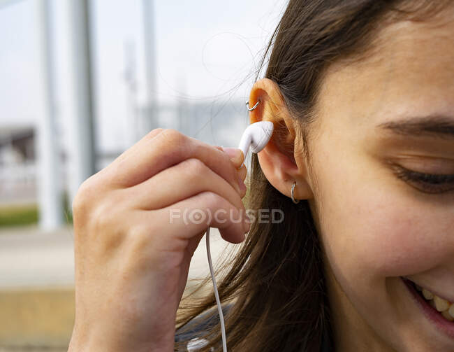 Mulher colocando um fone de ouvido branco em sua orelha. — Fotografia de Stock