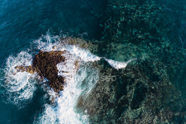Вид с воздуха на волну, прорывающуюся над острым лавовым рифом на Тенерифе. — стоковое фото