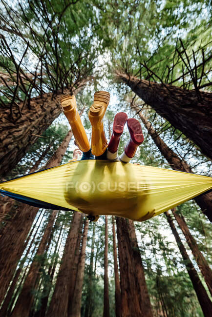 View from below of two children wearing boots in a hammock — Stock Photo