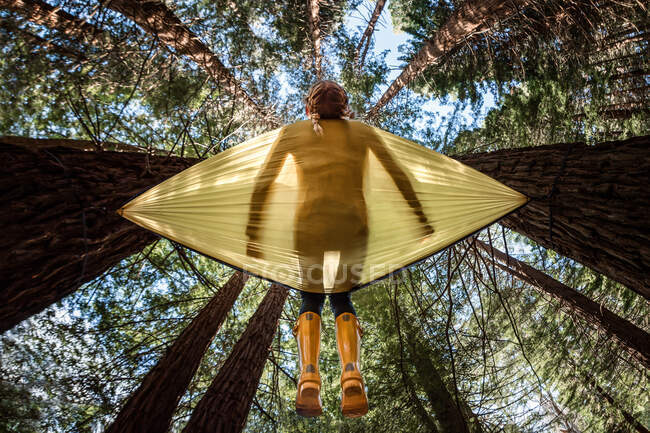 View from below of tween girl in yellow hammock — Stock Photo