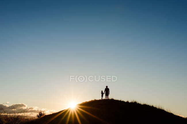 Silhouette von Vater und Sohn auf einem Hügel bei Sonnenuntergang — Stockfoto