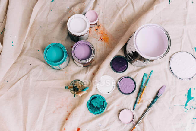 Latas de pintura de colores desde un ángulo alto en un paño de gota. - foto de stock