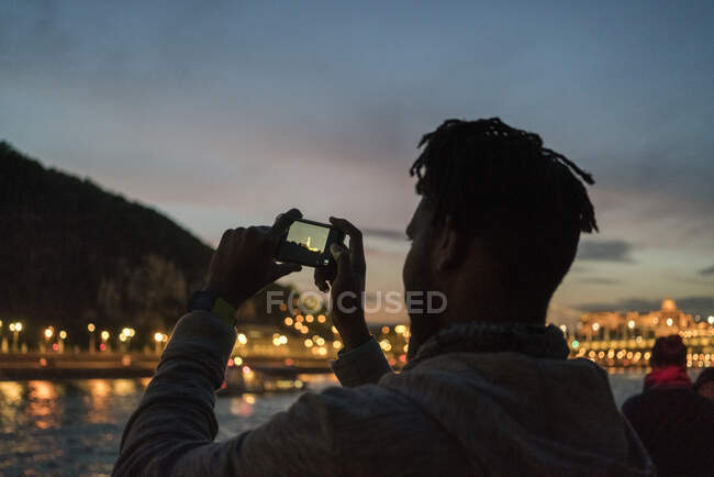 Homme africain prenant des photos d'un bateau la nuit à Budapest — Photo de stock