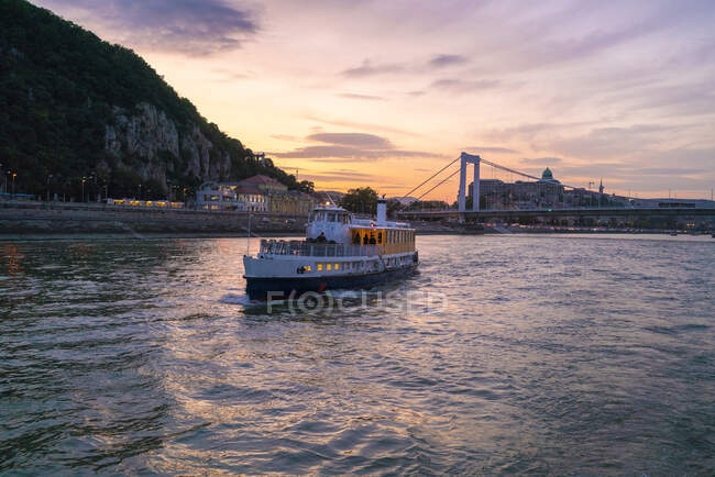 Круїзний човен з мостом Єлизавети і пагорбом на заході сонця. — стокове фото
