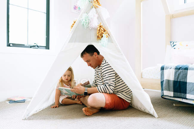 Счастливый отец и дочь проводят время вместе дома в палатке — стоковое фото