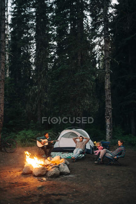 Um grupo de amigos se senta em torno de uma fogueira enquanto acampa em Oregon. — Fotografia de Stock