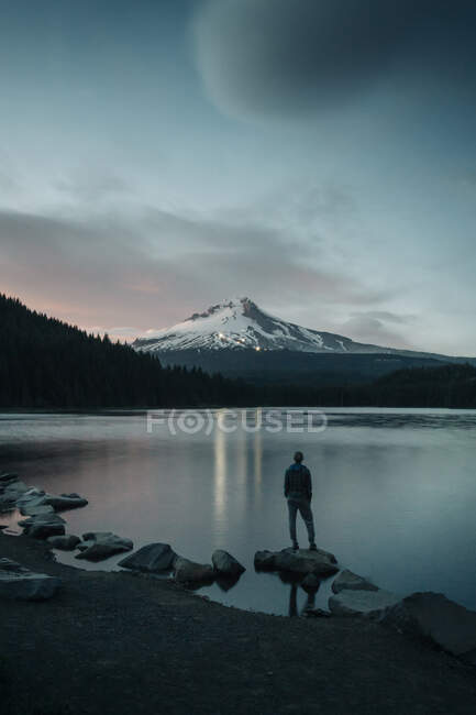 A young woman stands on the edge of Trillium Lake in Oregon. — Stock Photo