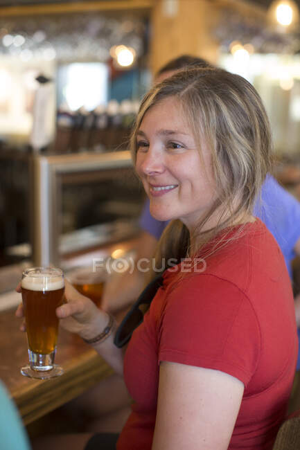 Eine junge Frau genießt ein Bier mit ihren Freunden in einer Bar in Oregon. — Stockfoto