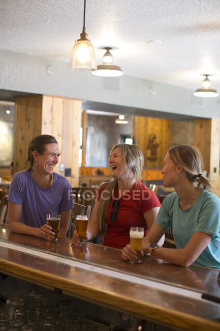 Trois amies dégustent une bière dans une brasserie du camp gouvernemental, OU. — Photo de stock