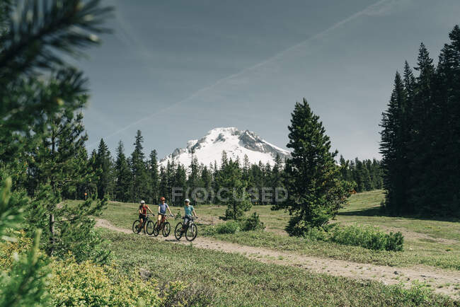 Threee women bike on a trail near Mt. Hood in Oregon. — Stock Photo