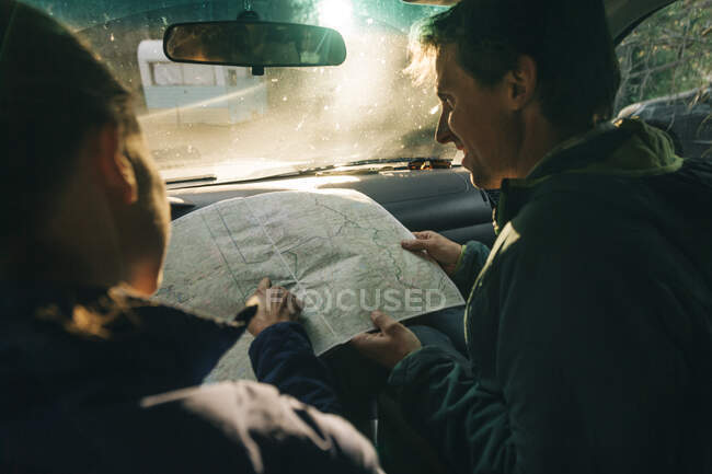 Ein junges Paar betrachtet auf einem Roadtrip die Landkarte. — Stockfoto