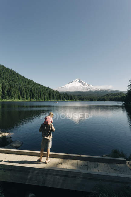 Un padre lleva a su hija sobre sus hombros en el lago Trillium, OR. - foto de stock
