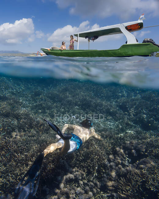 Young man snorkeling near the boat in ocean, underwater view — Stock Photo