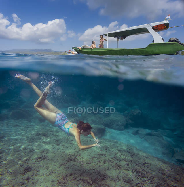 Mujer joven buceando cerca del barco en el océano, vista submarina - foto de stock
