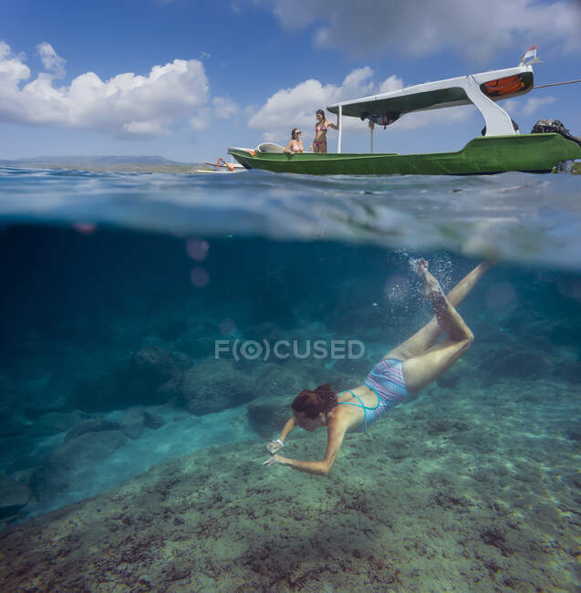 Молода жінка хропіння біля човна в океані, підводний вид — стокове фото