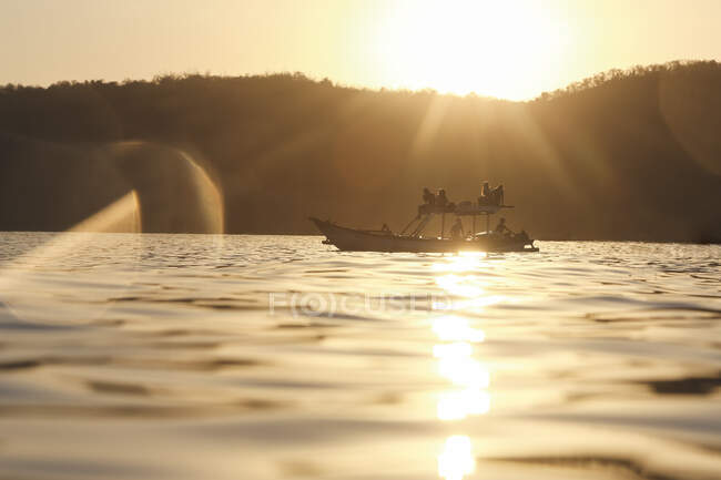 Группа людей на лодке на закате — стоковое фото