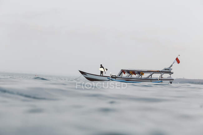 Surfista en el barco en un océano - foto de stock