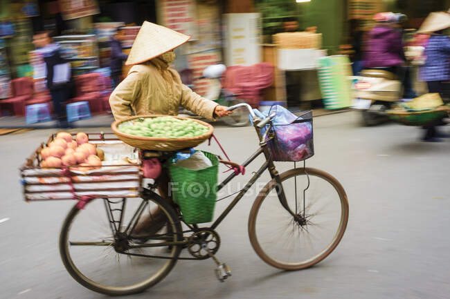 Mujer empujando una bicicleta en el casco antiguo, distrito de Hoan Kiem, Hanoi, Vietnam - foto de stock