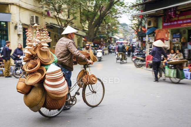 Man on bicycle selling Vietnamese hats in Old Quarter, Hoan Kiem District, Hanoi, Vietnam — Stock Photo