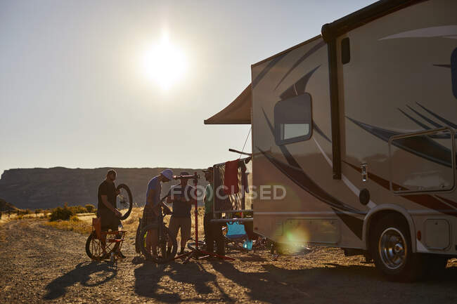 A group of guys working on mountain bikes at the rear of an RV. — Stock Photo