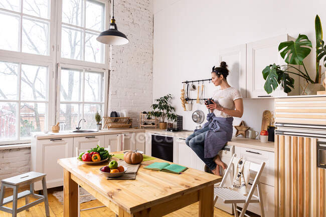 Mujer ama de casa joven y hermosa cocina en una cocina - foto de stock