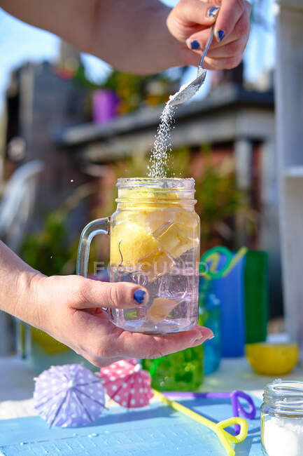 Donna preparare un cocktail, versare lo zucchero nel bicchiere con pezzi — Foto stock