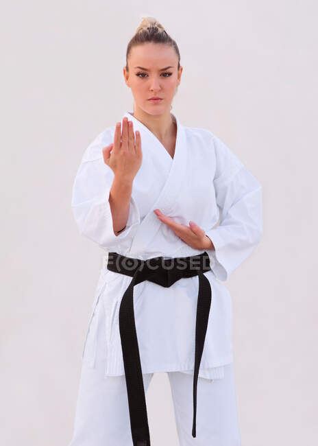 Joven experta en karate femenino practicando posiciones de lucha con su kimono - foto de stock
