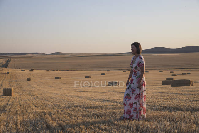 Mulher observando o campo seco ao pôr do sol — Fotografia de Stock