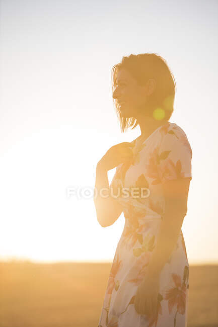 Mulher observando o campo seco ao pôr do sol — Fotografia de Stock