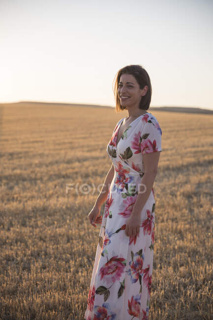 Frau beobachtet das trockene Feld bei Sonnenuntergang — Stockfoto