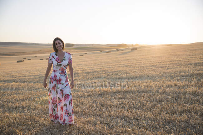 Femme observant le champ sec au coucher du soleil — Photo de stock