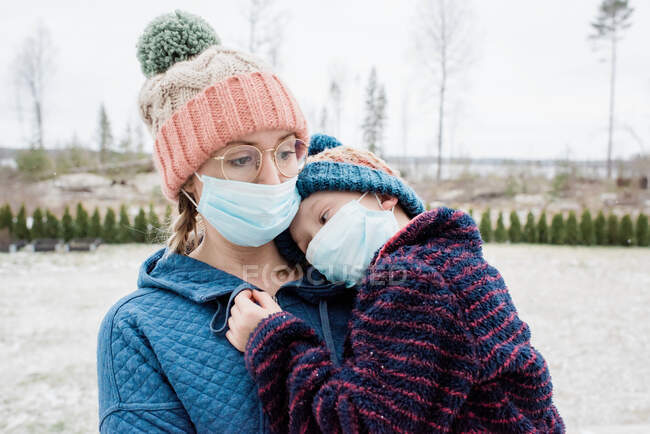 Mãe carregando filho com máscaras faciais em como proteção contra vírus & gripe — Fotografia de Stock