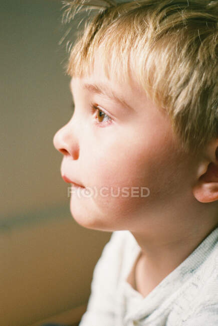 Маленький хлопчик, який дивиться у вікно, знятий на плівку . — стокове фото