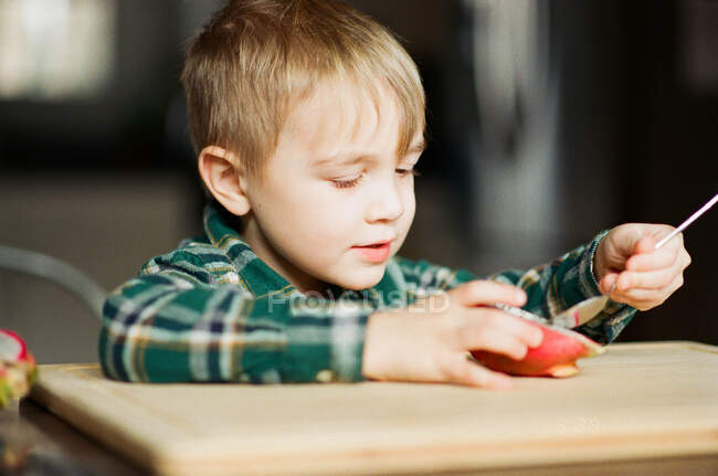 Piccolo ragazzo mangiare un drago frutta con un cucchiaio. — Foto stock