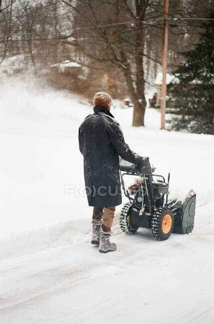Film foto di un uomo neve che soffia nel suo vialetto. — Foto stock