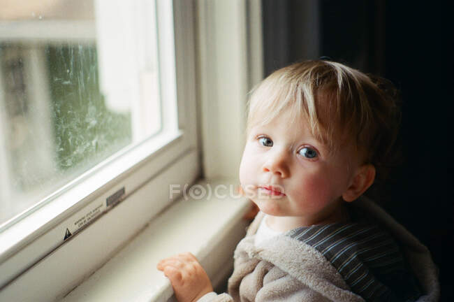 Film photo of a little girl standing by a window. — Stock Photo
