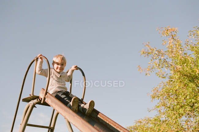 Little boy going down a slide. — Stock Photo