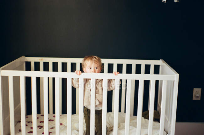 Little girl standing up in her crib. — Stock Photo