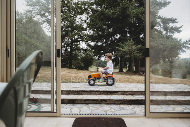 Vue à travers les portes du garçon sur tracteur jouet — Photo de stock