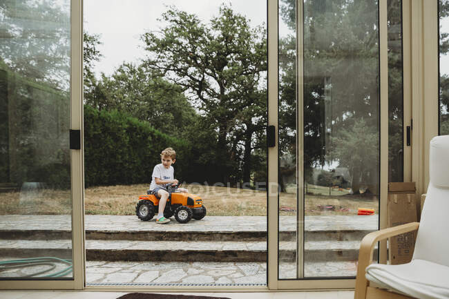 Vista attraverso le porte del ragazzo sul trattore giocattolo — Foto stock