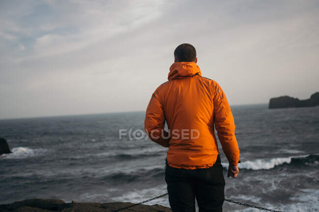 Молодой человек, стоящий на ветреном пляже Дирли, Исландия — стоковое фото