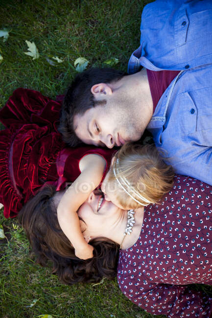 Молодая пара целует дочь на траве в Детройт MI — стоковое фото