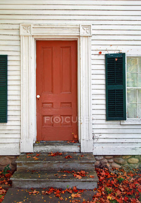 Maison coloniale avec porte orange à l'automne — Photo de stock