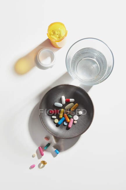 Пляшка таблеток зі склом води і риби — стокове фото