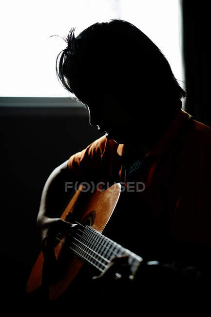Silueta de niño tocando la guitarra - foto de stock