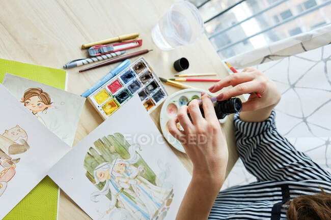 Тисячолітня дівчинка малює чудові зображення на папері, сидячи вдома. — стокове фото